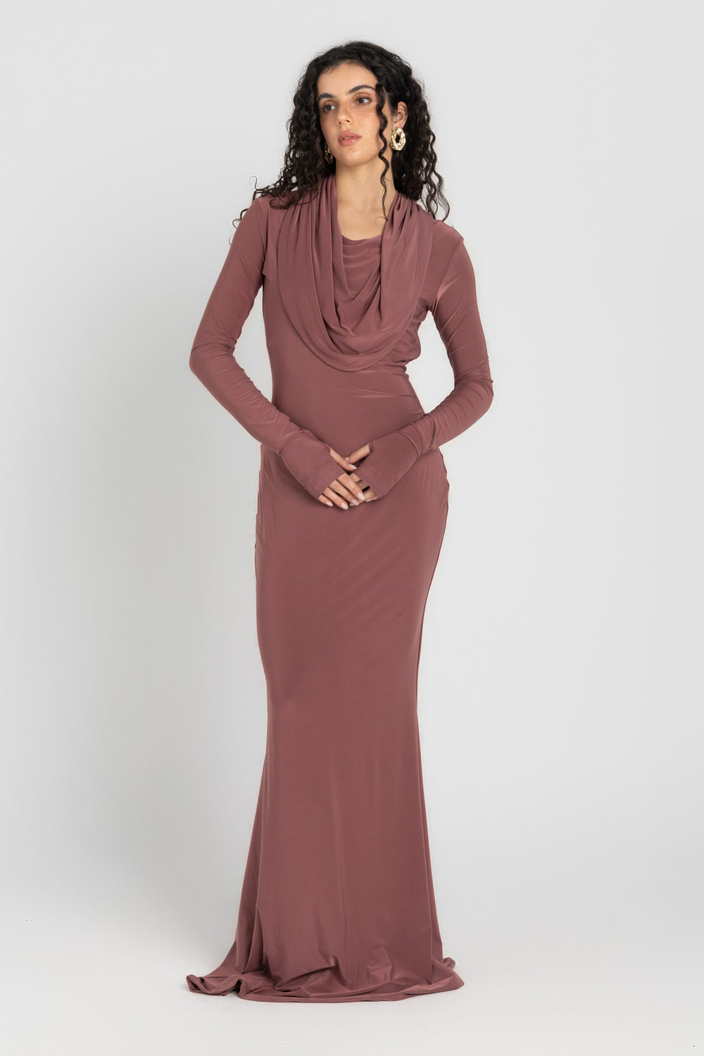 Woman wearing a long, cashmere dress with a hood on a white background