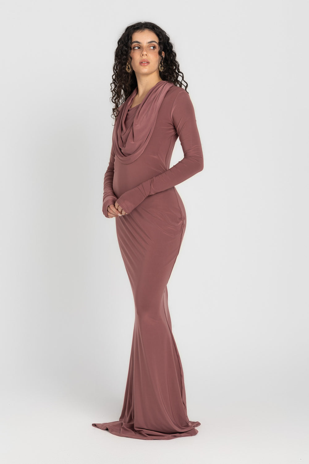 Woman wearing a long, cashmere dress with a hood on a white background
