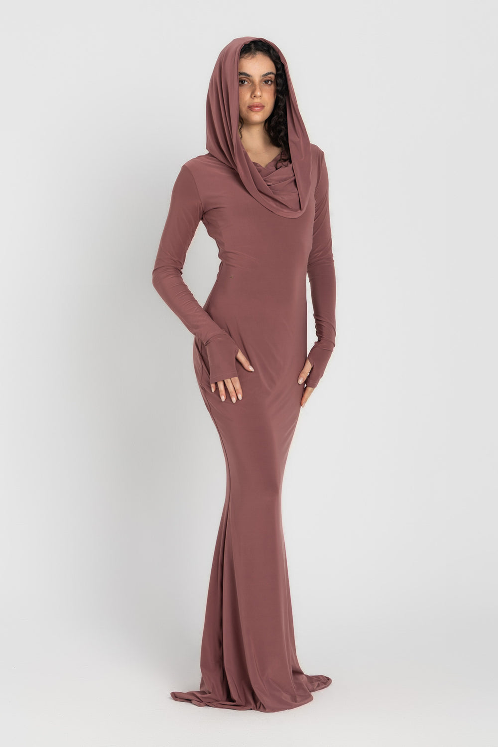 Woman wearing a long, cashmere dress with a hood on a white background