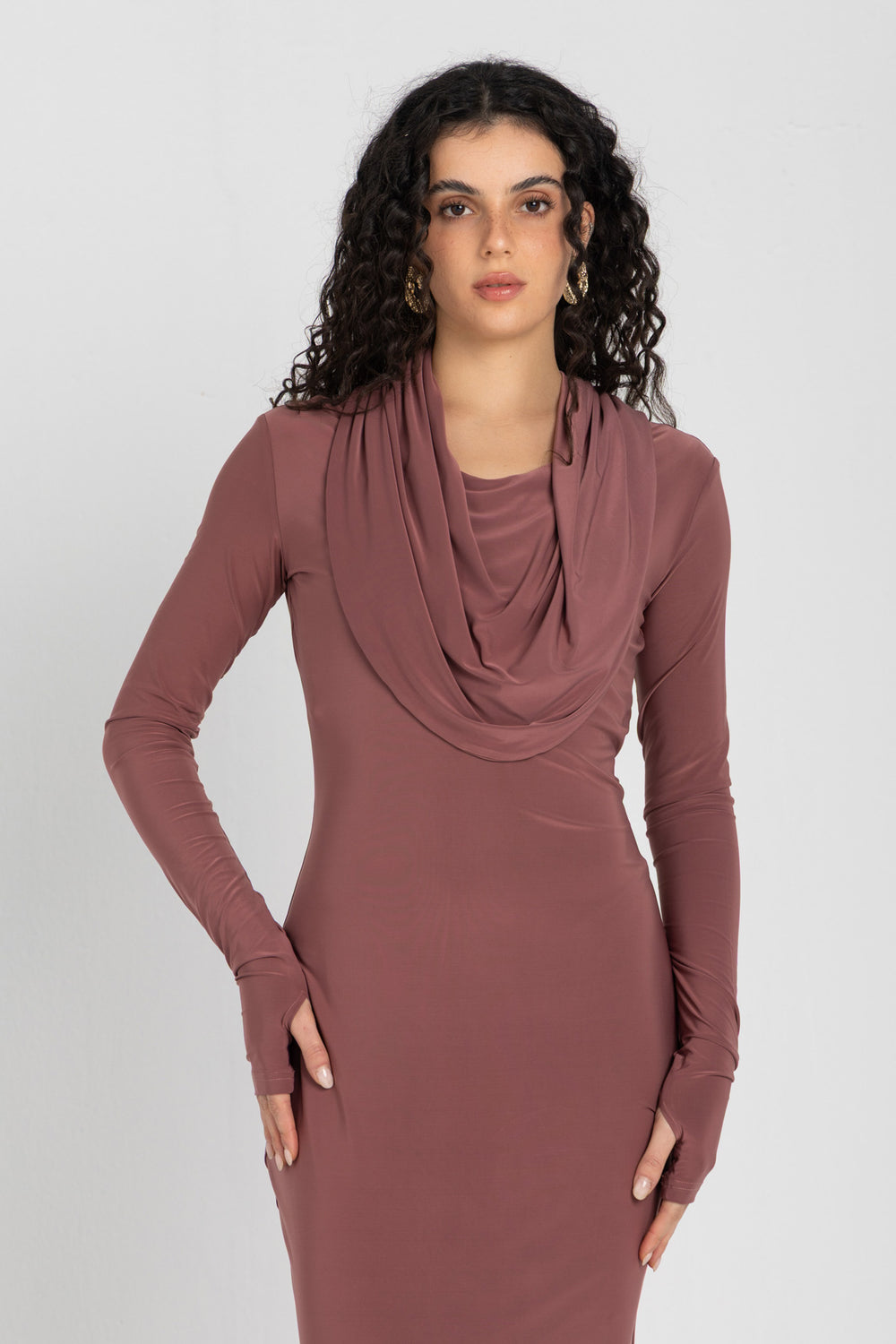 Woman wearing a long, cashmere dress with a hood on a white background