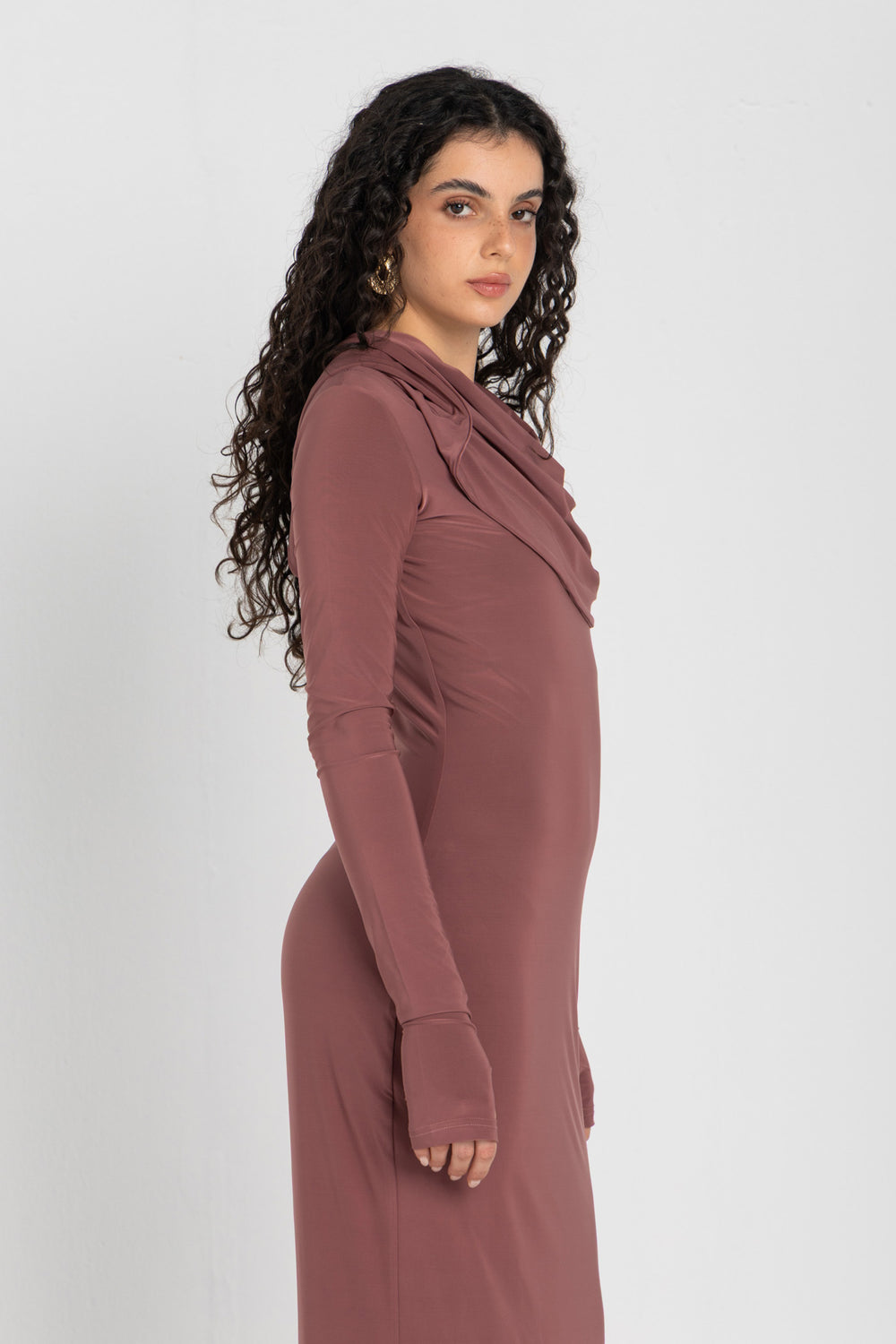 Woman wearing a long, cashmere dress with a hood on a white background