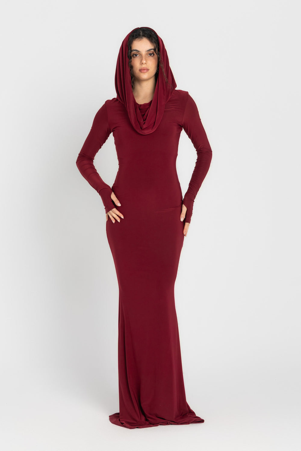 Woman wearing a burgundy long-sleeve dress with a hood on a white background