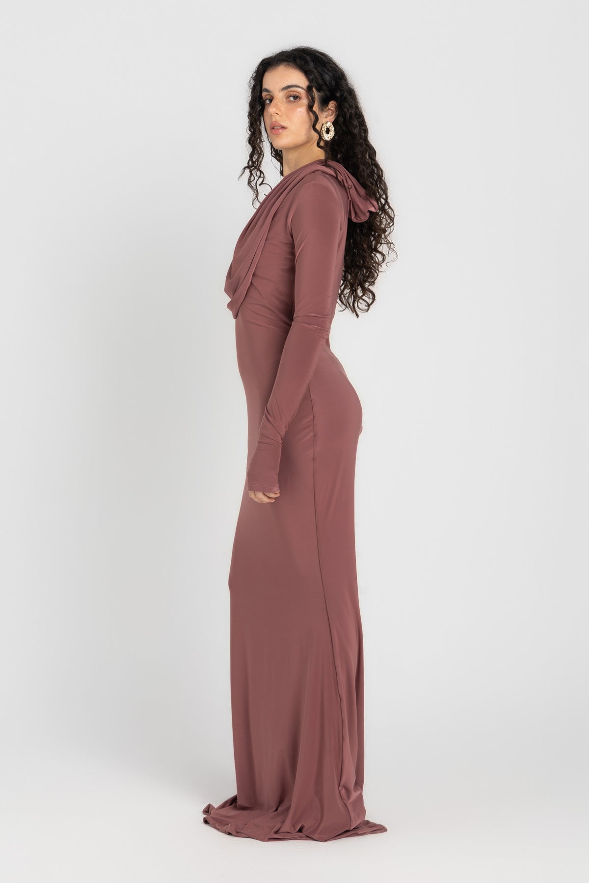 Woman wearing a long, cashmere dress with a hood on a white background