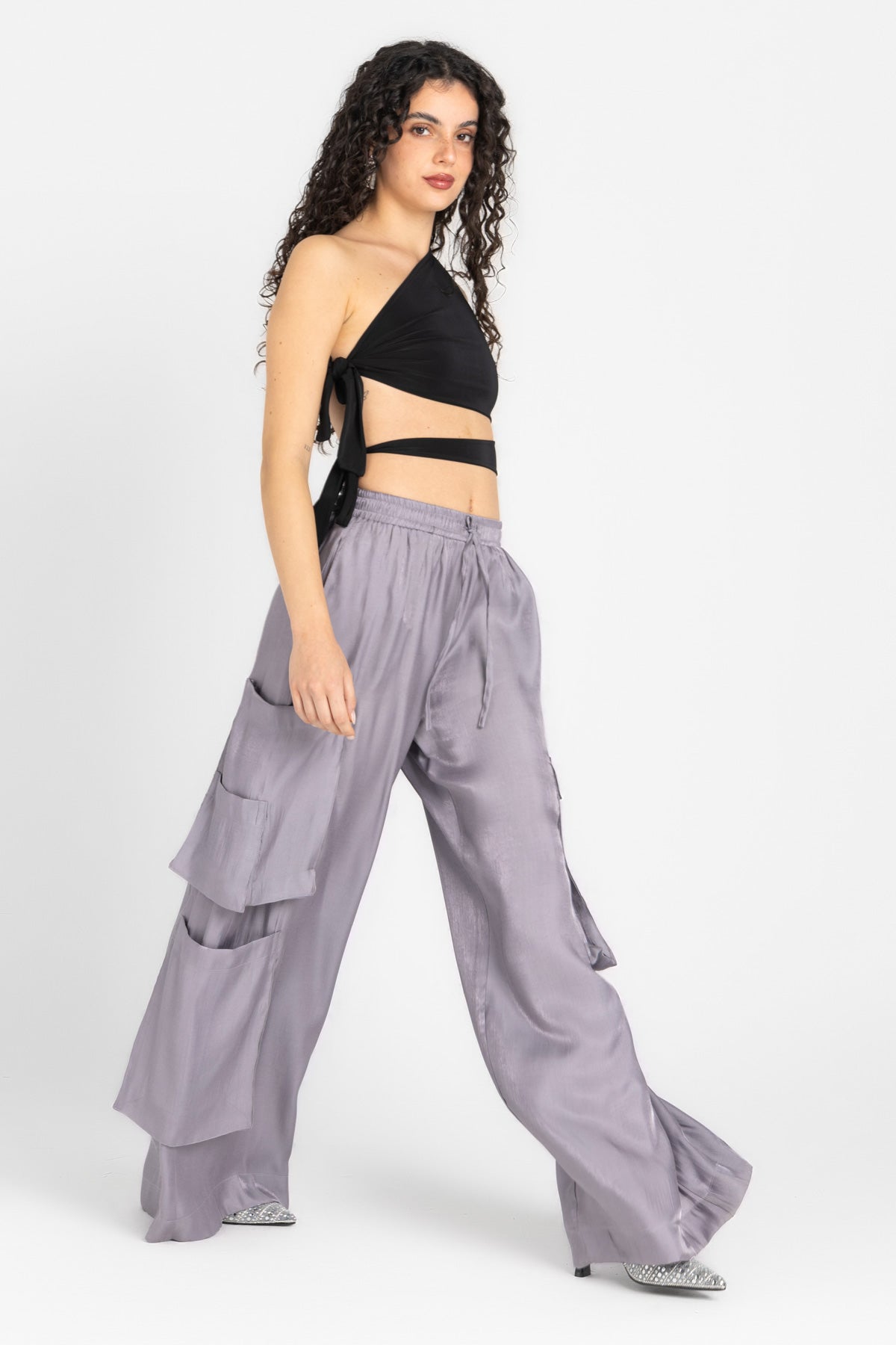 Woman wearing a black top and gray layered pants on a white background