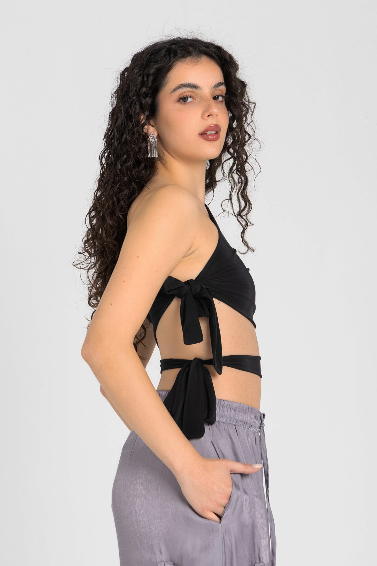 Woman wearing a black halter top and gray pants on a white background
