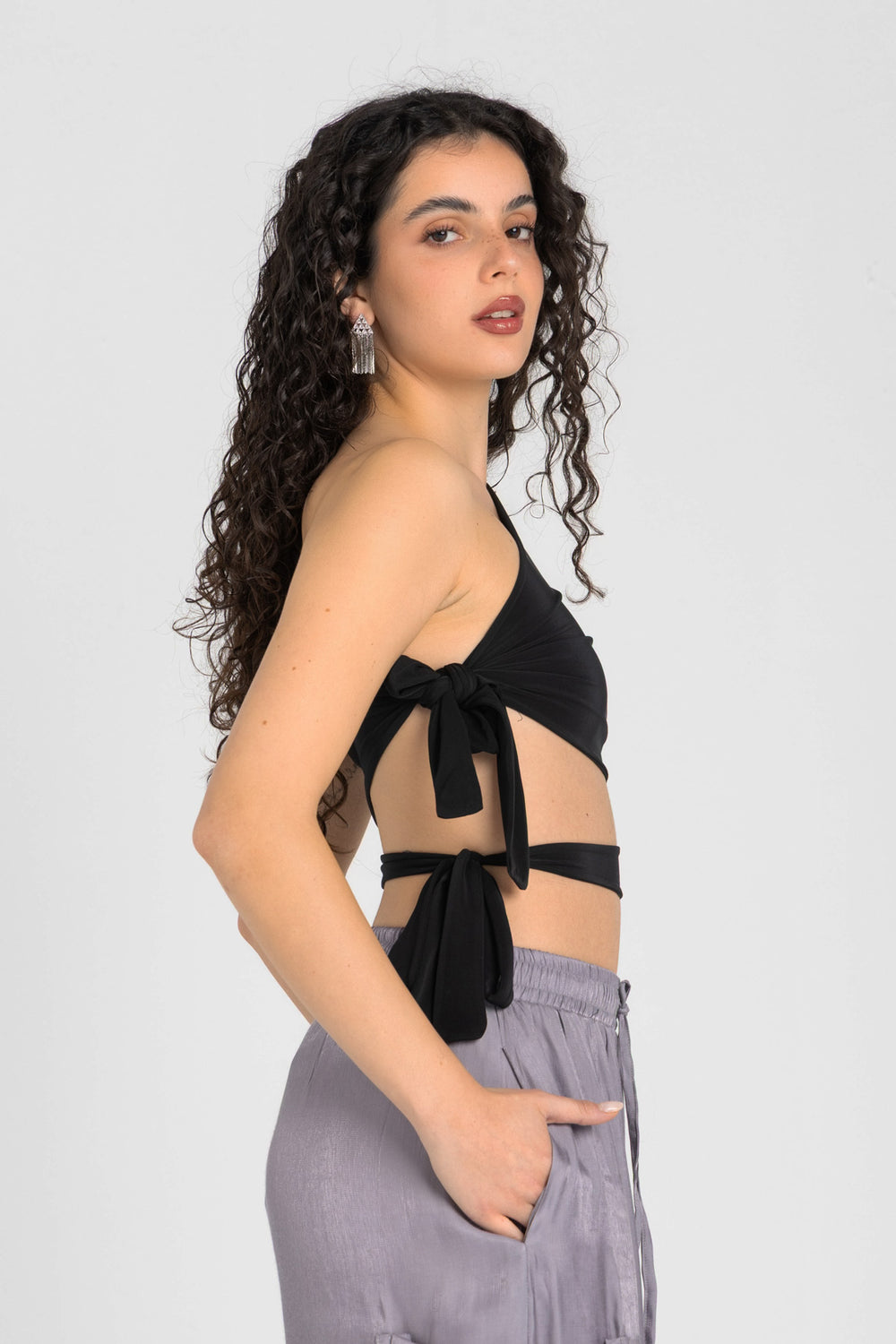 Woman wearing a black halter top and gray pants on a white background