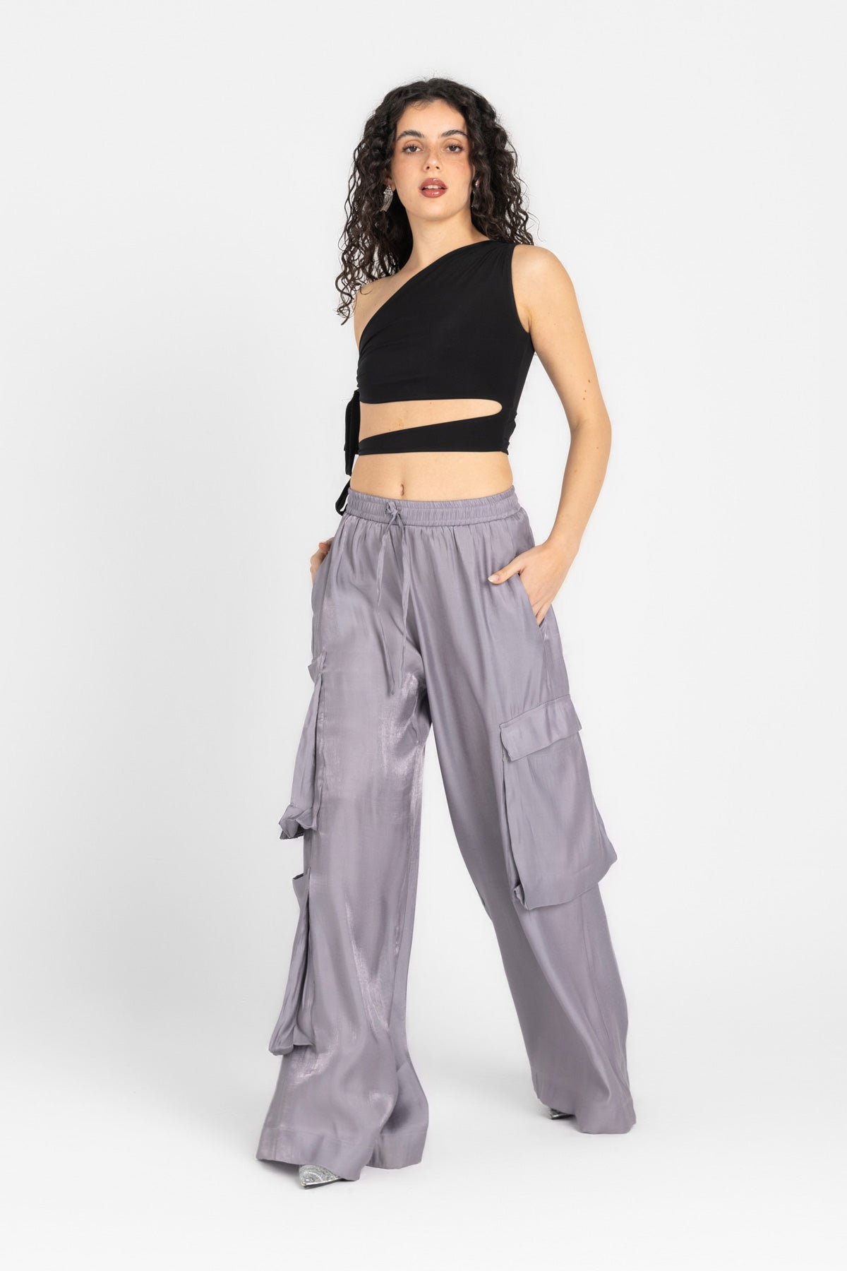 Woman wearing a black crop top and gray cargo pants on a white background