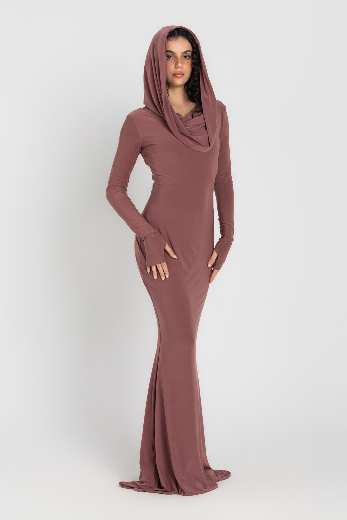 Woman wearing a long, cashmere dress with a hood on a white background