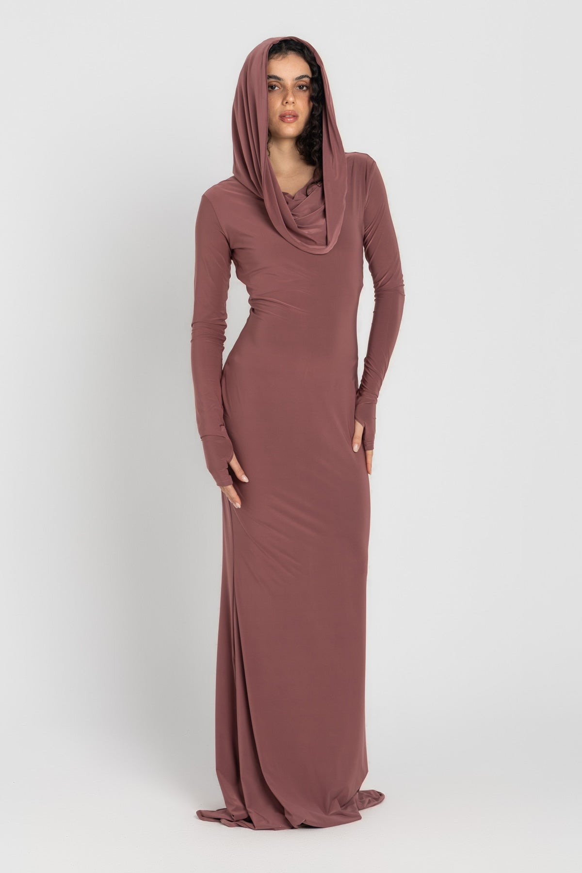 Woman wearing a long, cashmere dress with a hood on a white background